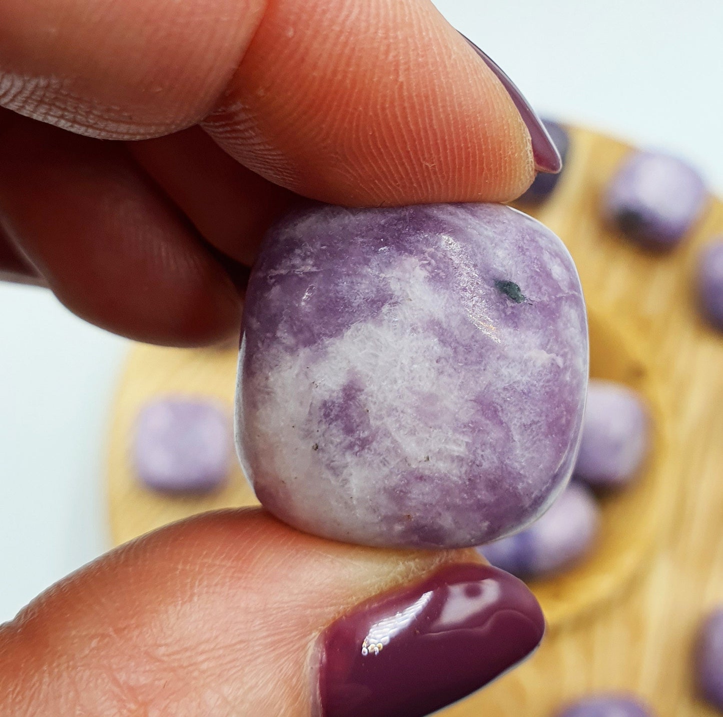 May include: A tumbled purple and white lepidolite crystal with a smooth, rounded surface.